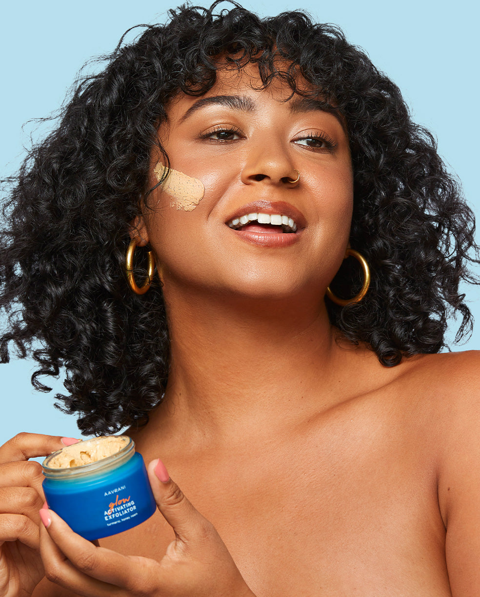 Model Image with product swatch on cheek, holding mask. 